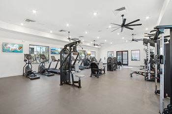 A gym with weights and cardio equipment in a building with white walls
